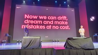 A wide-angle photo of two men standing on a stage during the Upscale Conference in Malaga, with a large screen behind them displaying the red text: "Now we can drift, dream and make mistakes at no cost."