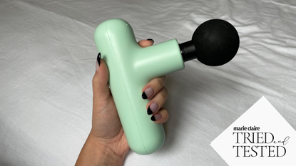 best massage guns: hand holding a green massage Lola gun