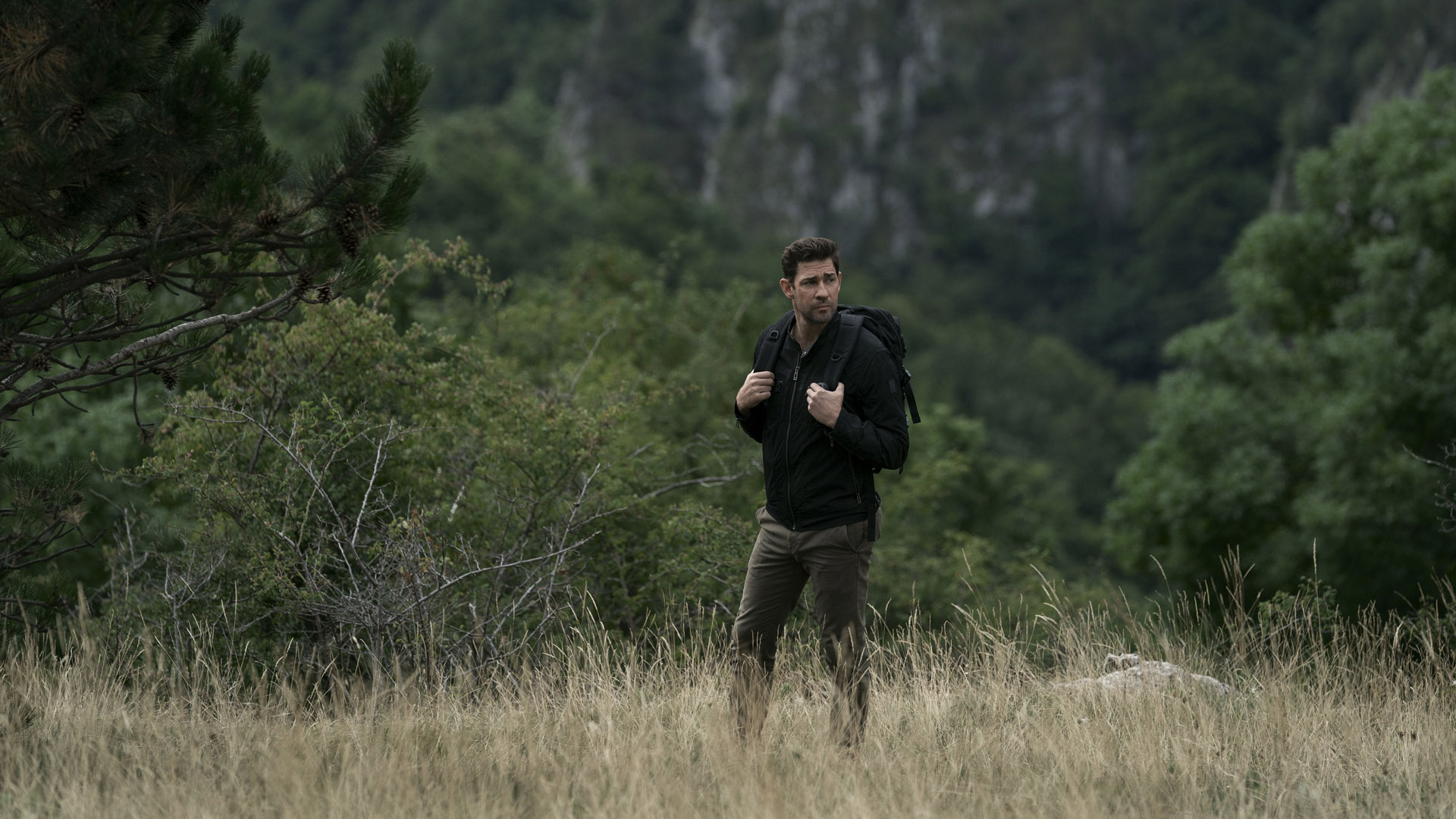 Jack Ryan walks across an open field with a backpack on in Tom Clancy's Jack Ryan season 3
