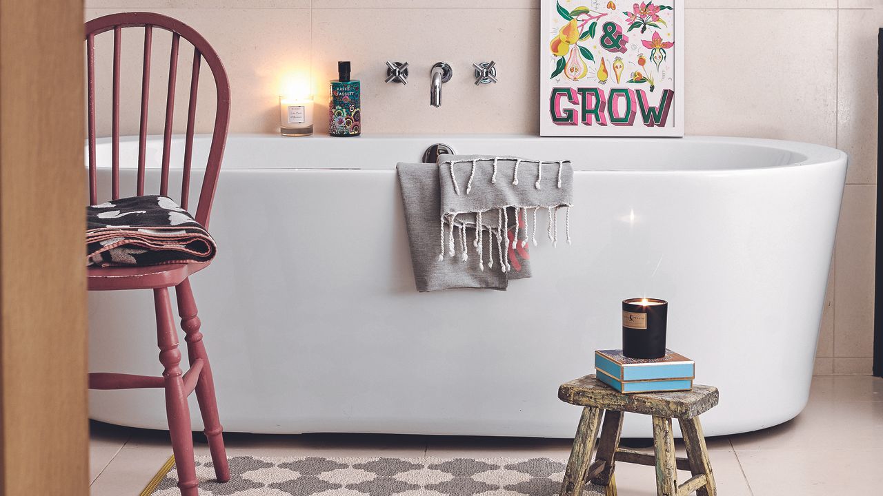 Bathroom with white freestanding tub, red chair and stool