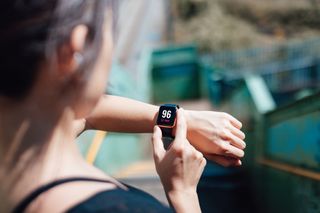 Exercise errors: Over the shoulder view of a young woman wearing smart watch, using fitness app to check her training progress