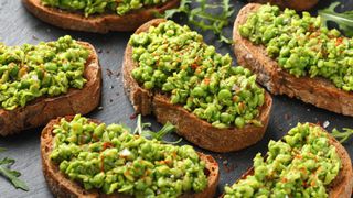 Small slices of toast laid out together with mashed peas and chilli flakes on top
