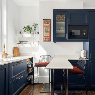 Kitchen with blue cupboards, white walls and white island with stools
