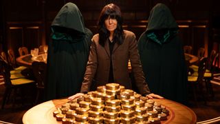 Claudia Winkleman next to a pile of gold and flanked by two hooded figures for The Traitors season 2