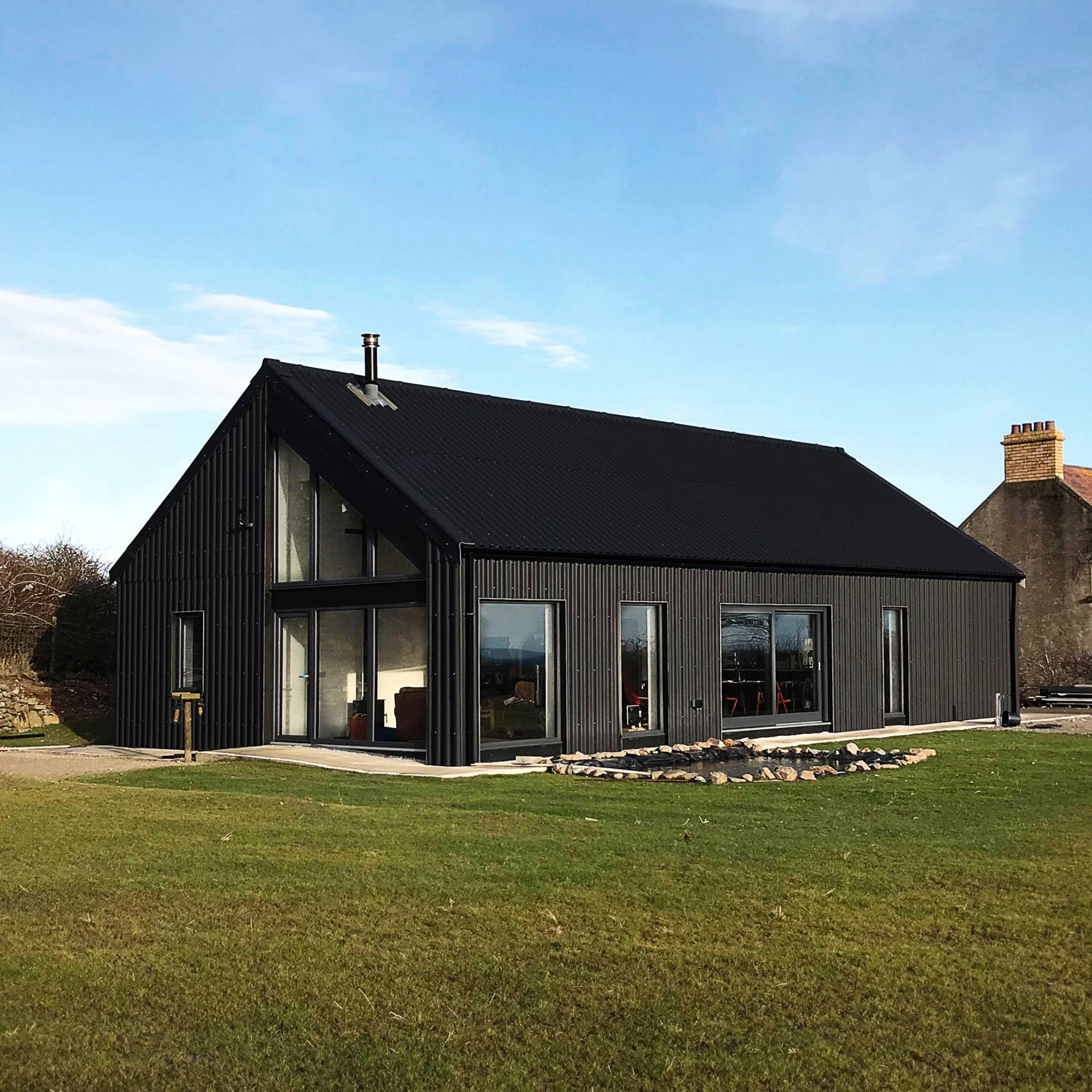 black fibre cement cladding on new build house with gardens