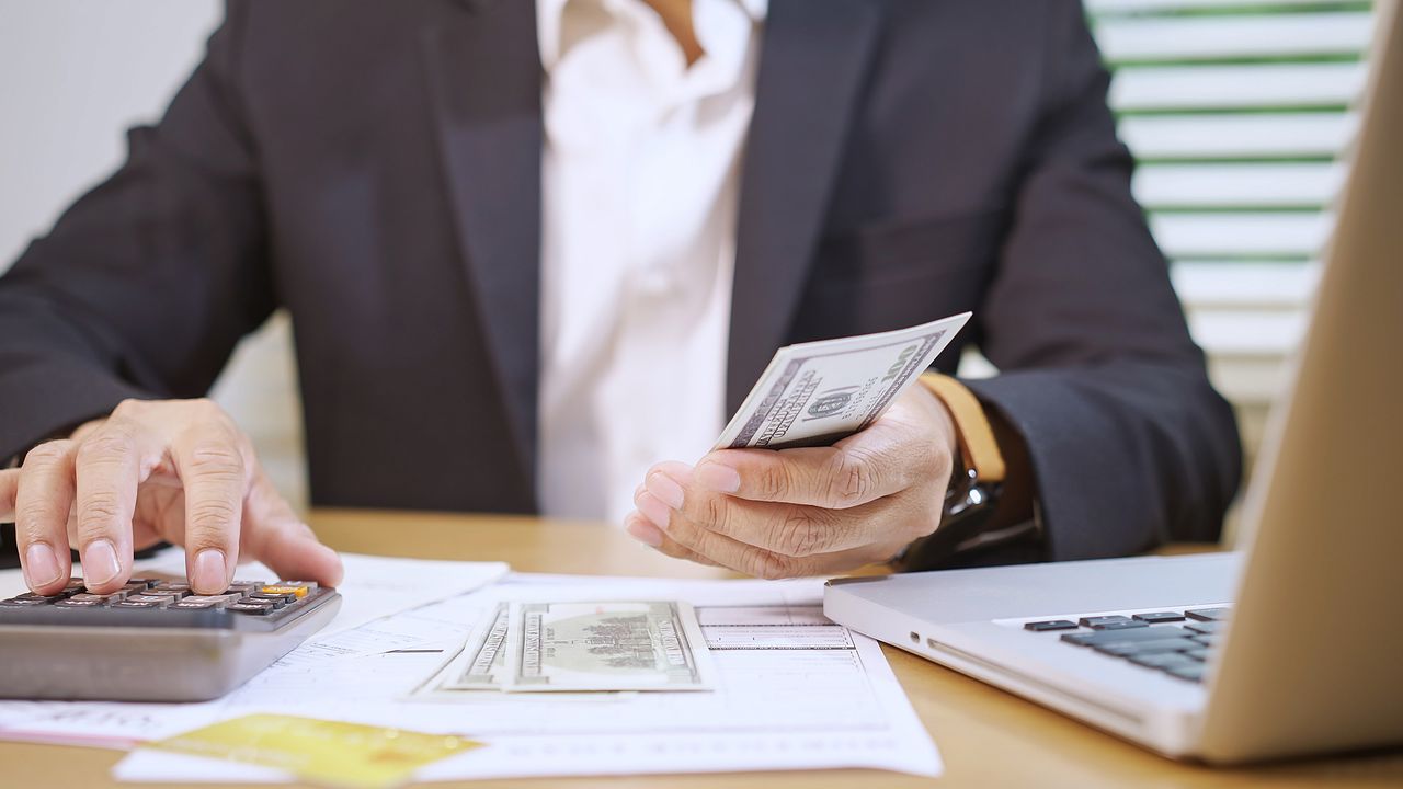 Man Managing Finances with Cash and Calculator