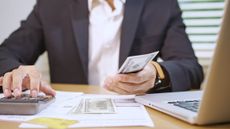 Man Managing Finances with Cash and Calculator