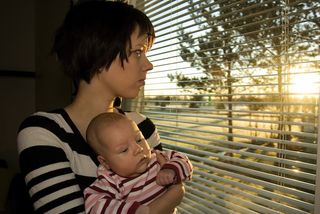 A sad mom looks out the window.