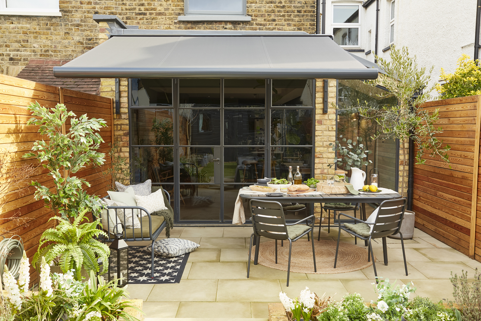 A modern patio area with an awning suppling shade to an outdoor seating area