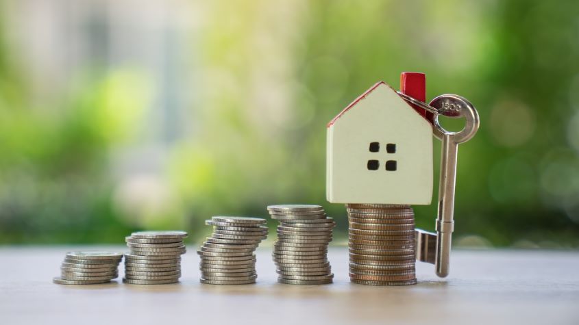 Stacks of coins next to a model house