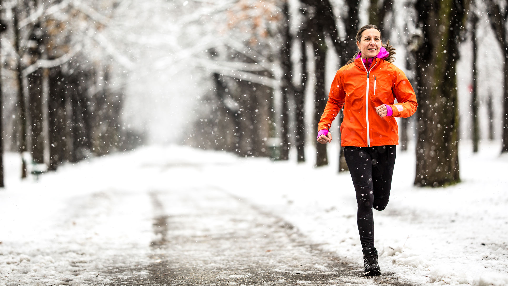 A young woman running in a snowy park 