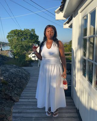 Nnenna Echem in a white outfit with matching white thong sandals.