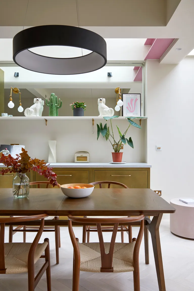 Brass kitchen against white wall with dark wood dining table and chairs