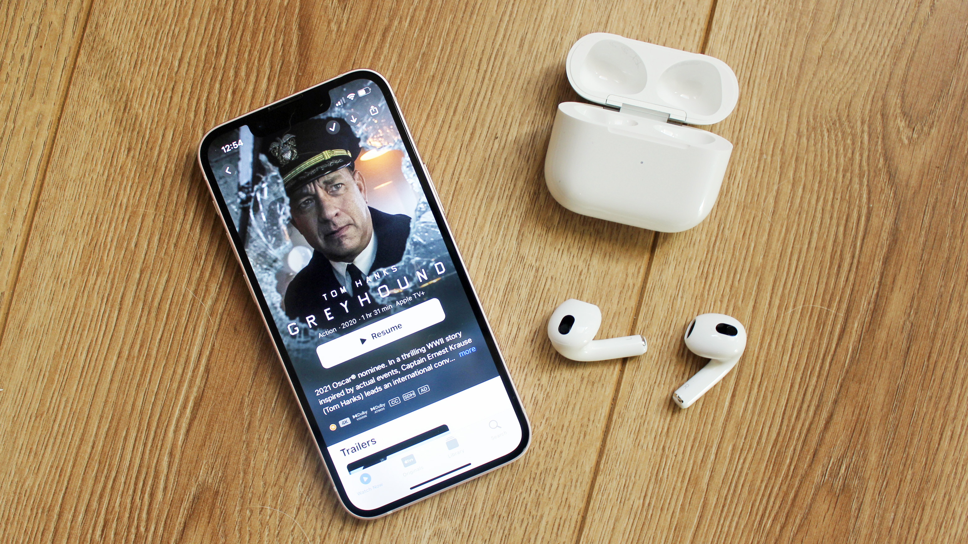 the airpods 3 next to an iphone 13 mini displaying apple tv