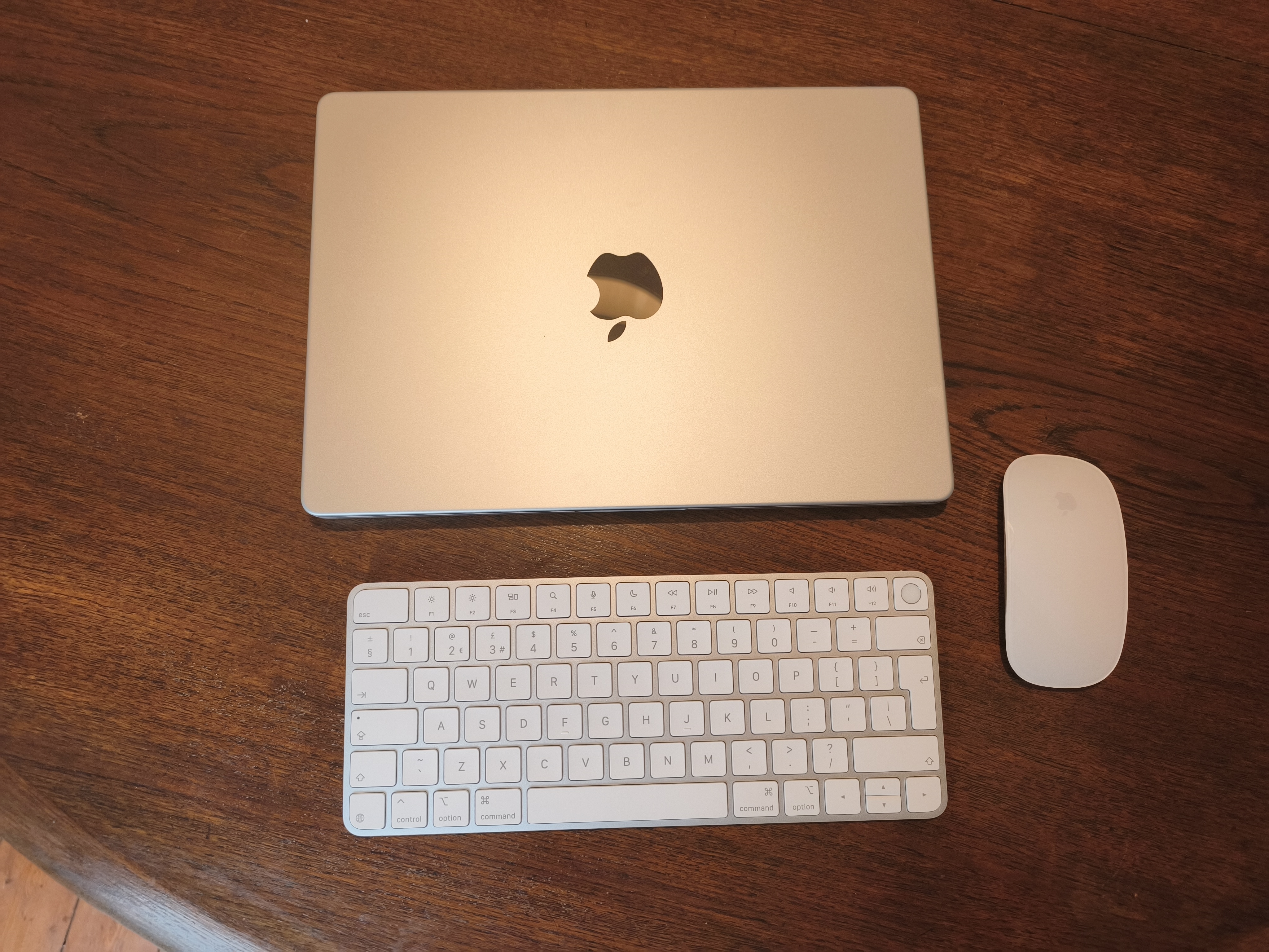 MacBook Pro M5 Max on a dining room table with Apple accessories the Magic Keyboard and Magic Mouse