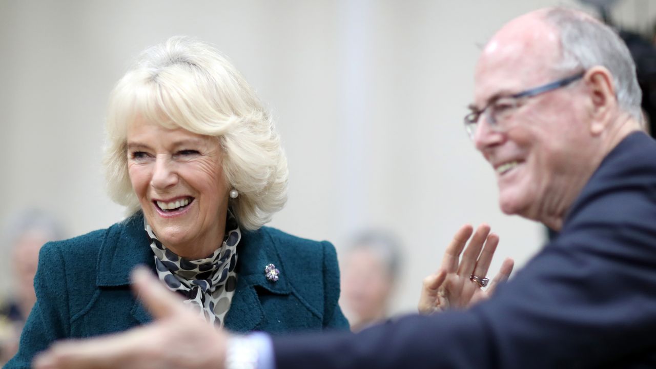 Queen Camilla standing and laughing with photographer Arthur Edwards at a 2017 tea party