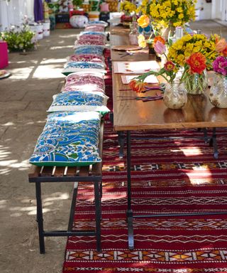 table with flowers and benches with cushions, rug