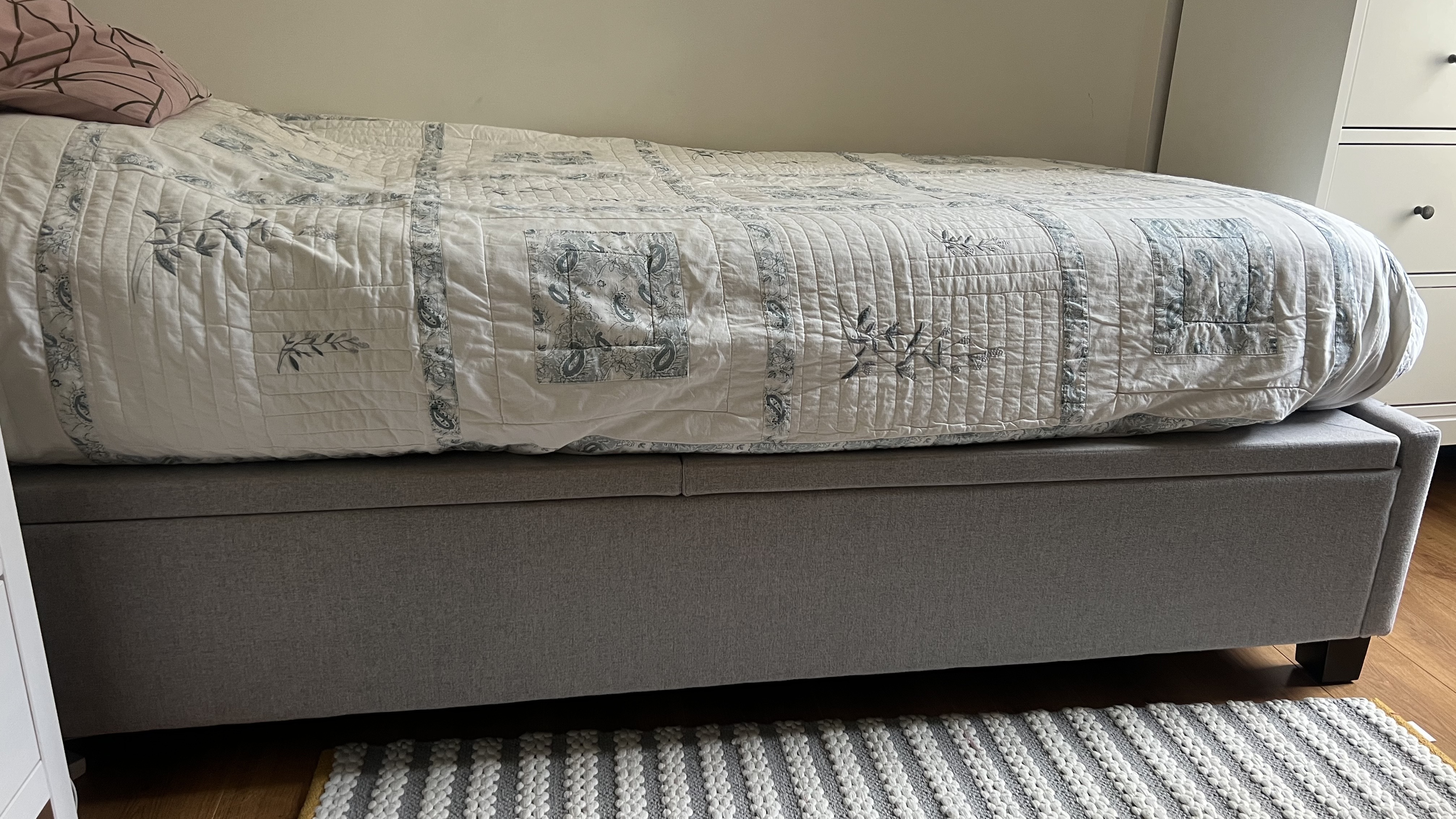 A grey Ikea storage bed base with mattress on top