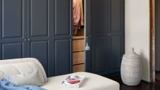 A bedroom with a blue clothes closet, a woven storage basket and a white fainting sofa