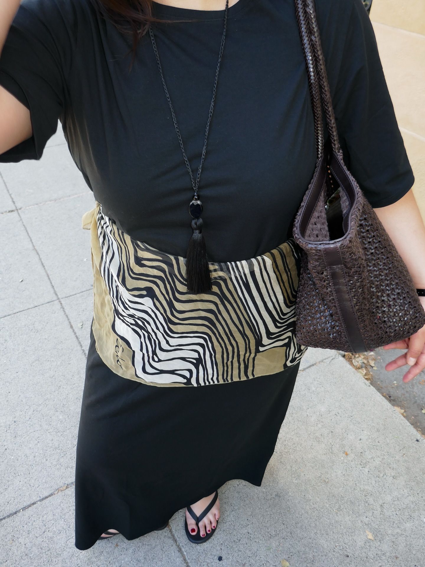 An image of @marina_torres wearing a black waisted dress with a rope necklace.