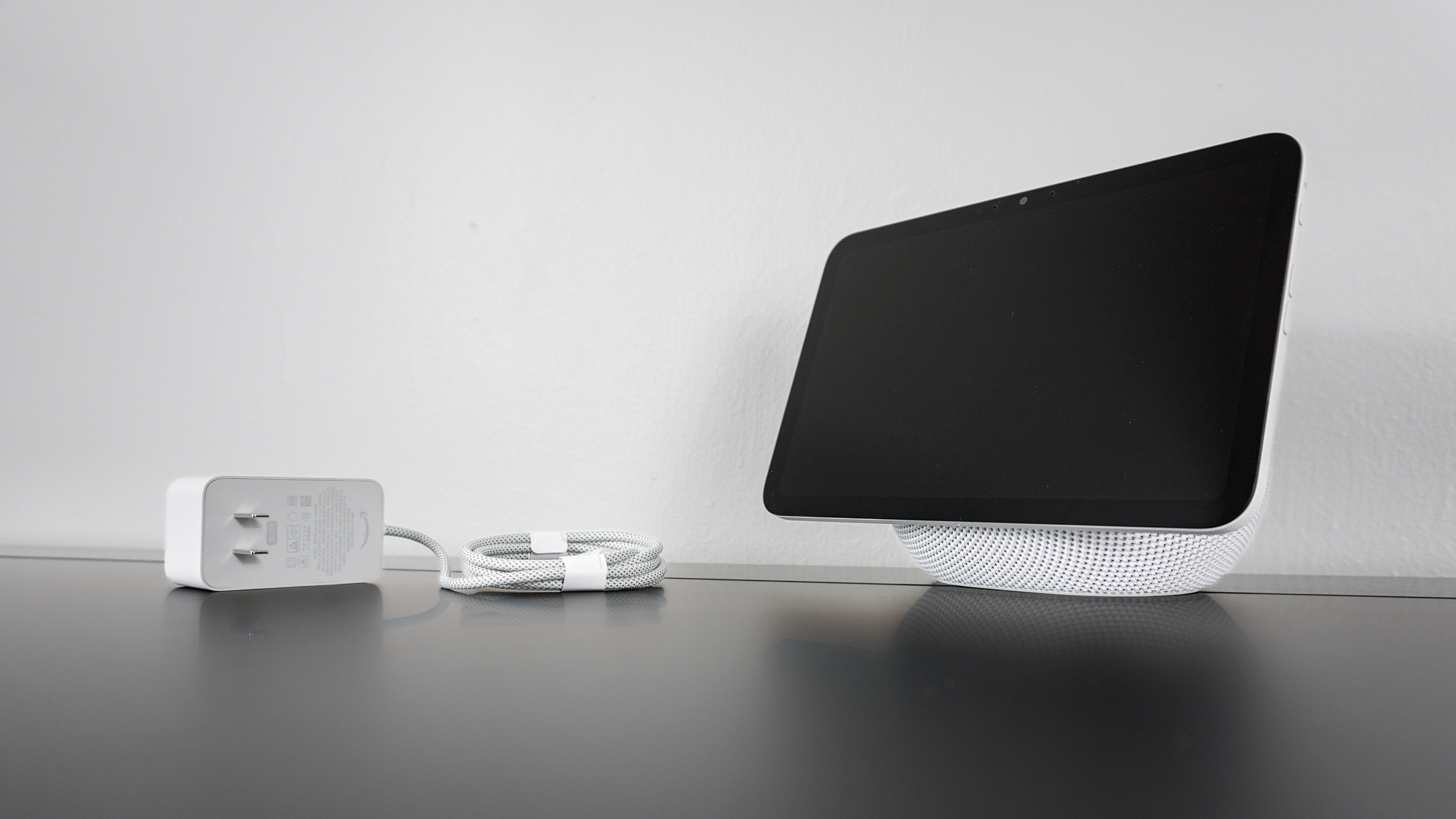 The Echo Show 8 (4th Gen) unboxed on a desk next to its power adapter