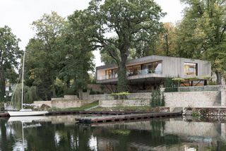 this modernist-inspired wood-clad home sits by a lake