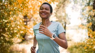 Woman smiling while listening to music through wired headphones on a run