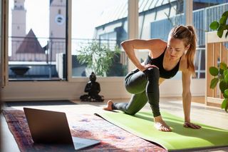 A woman exercising at home in front of her laptop