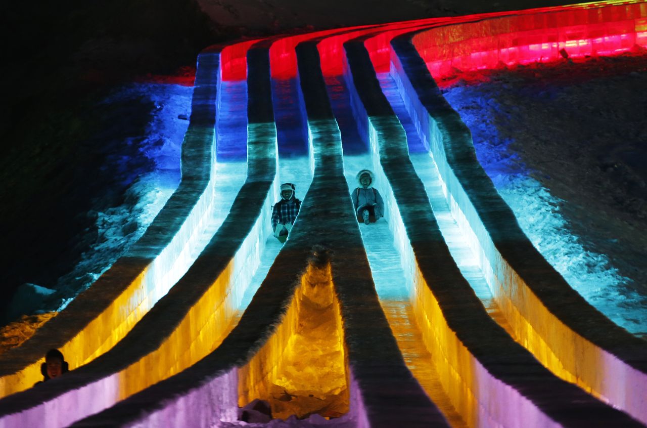 People ride the slides on the ice sculptures during the Harbin International Ice and Snow Festival.