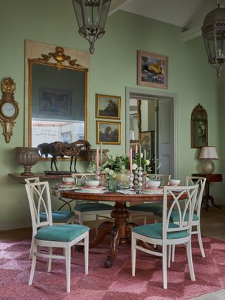 White chairs with blue cushions, round dining table, green and pink candles