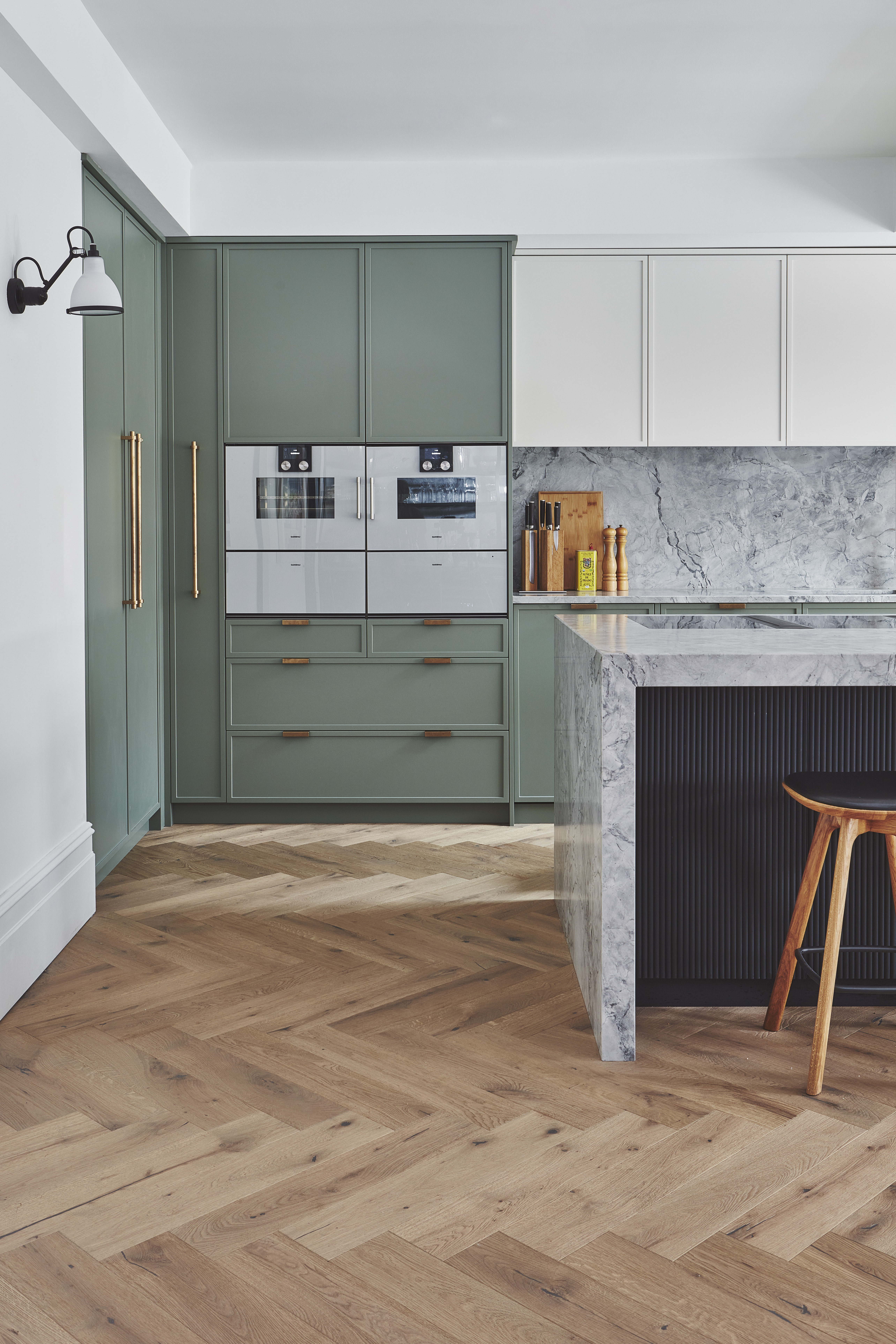 modern kitchen with stone counters and a mix of sage green and white cabinetry