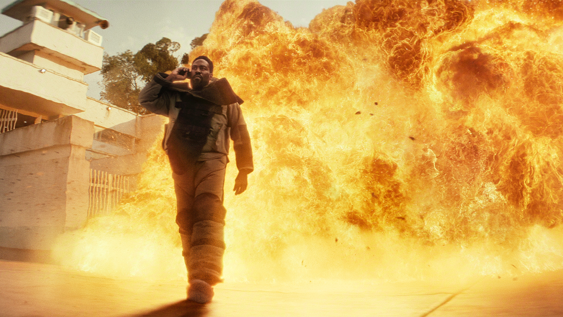 Yahya Abdul-Mateen II as John Creasy, standing in front of a big explosion, in Episode 1 of Man on Fire.