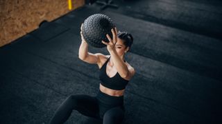 a photo of a woman doing weighted sit-ups with a medicine ball