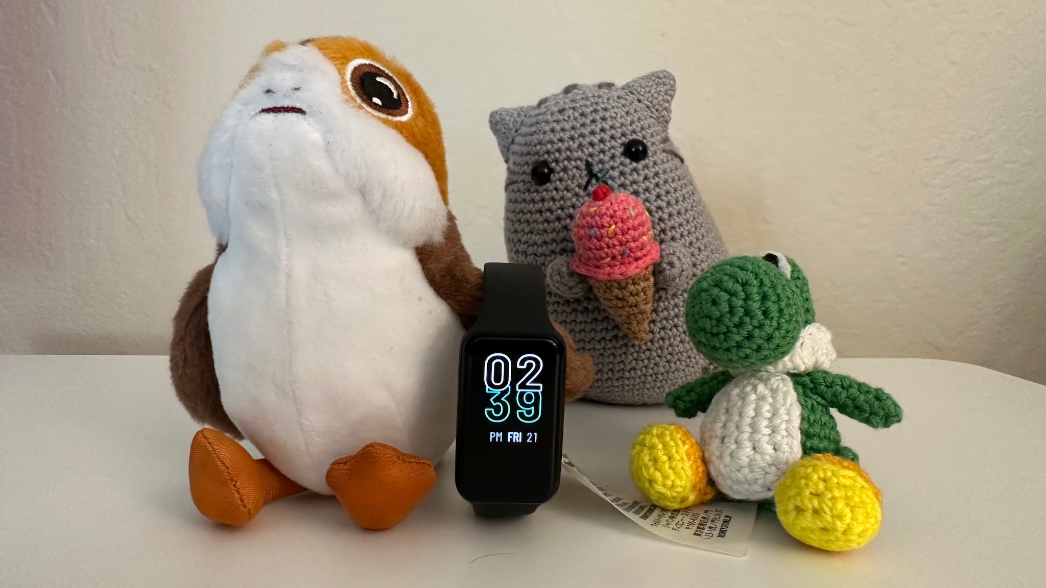 The Amazfit Band 7 sitting next to small stuffed animals to show its petite size.