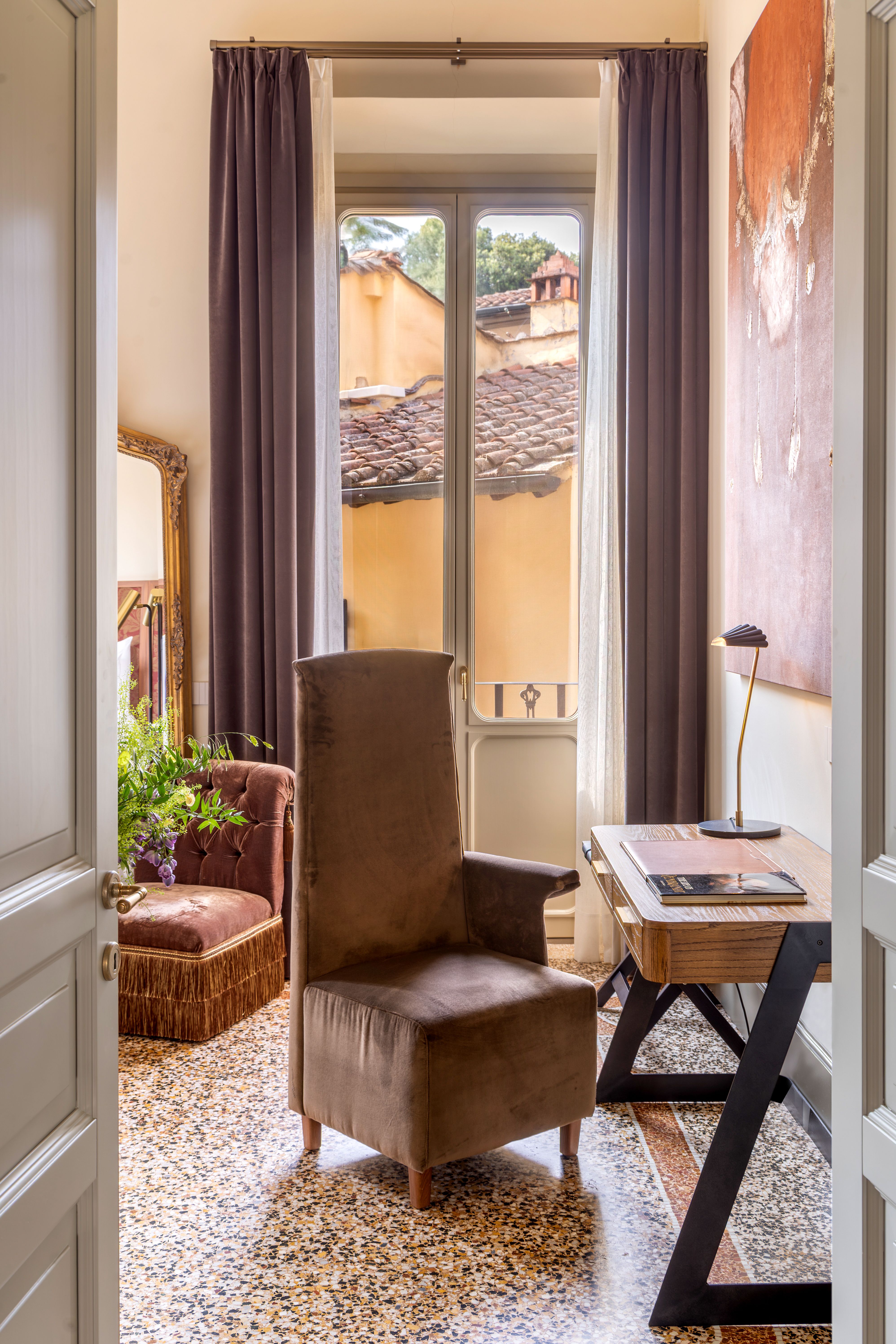 An ornate, palatial residence filled with sunshine, frescoed walls, terrazzo floors, vintage, modern, and plush contemporary furnishings, and thriving plants, whether indoors or on its terrace.