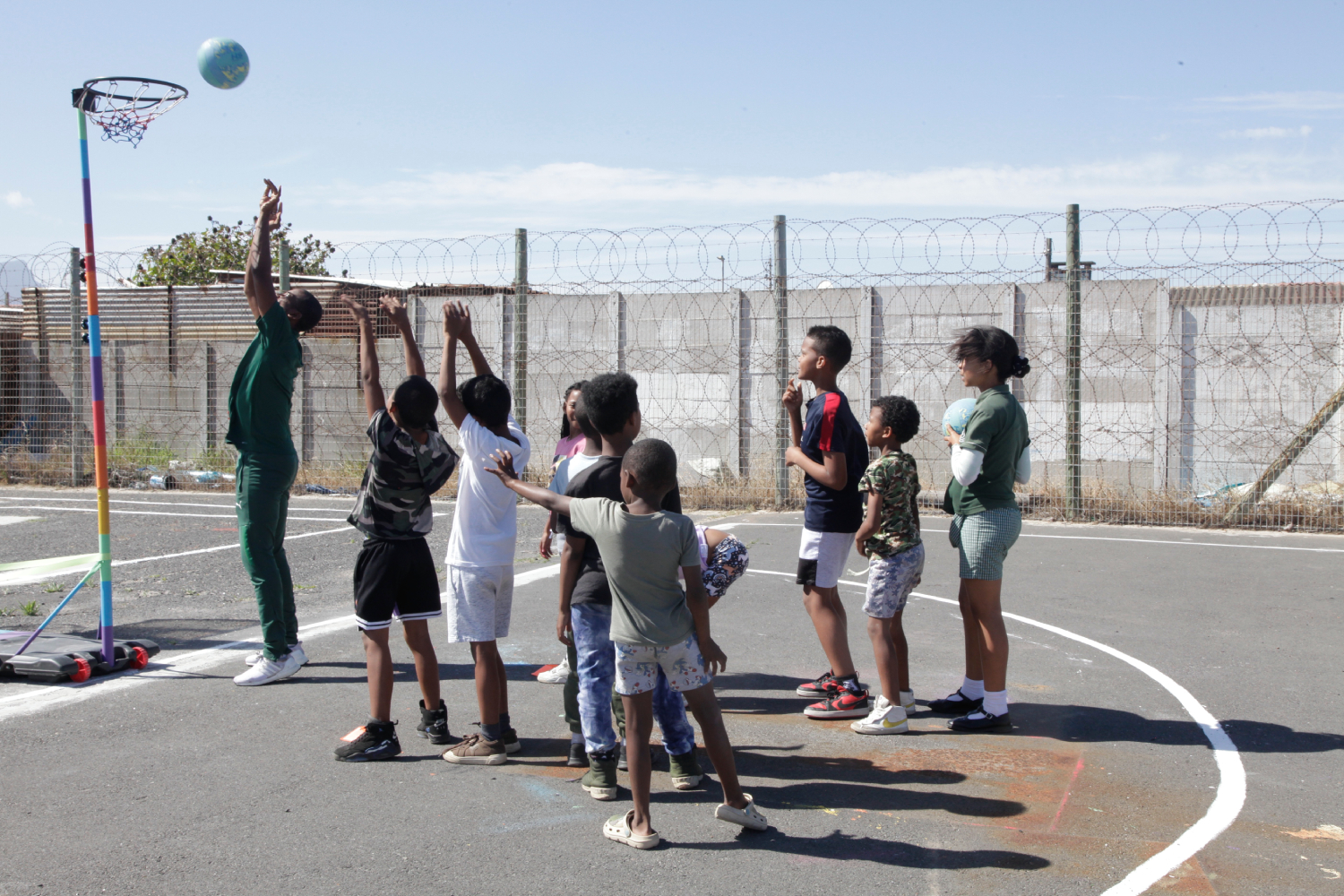 The barbed wire is there to keep the danger out, giving the children a space where they can just be kids