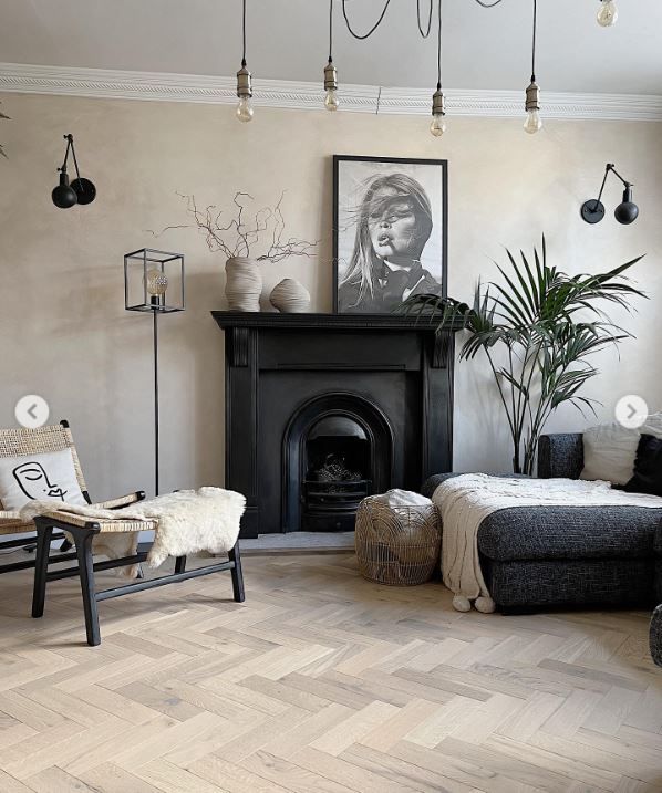 A living room with a fireplace in the middle and chair to the left