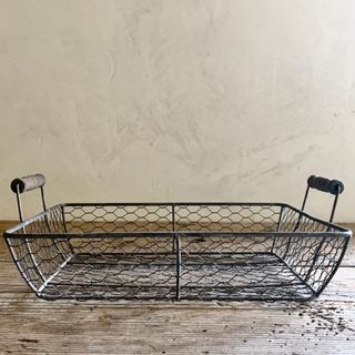 wire basket with handles to hold fruit and vegetables on a kitchen table