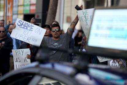 People hold signs protesting against Uber