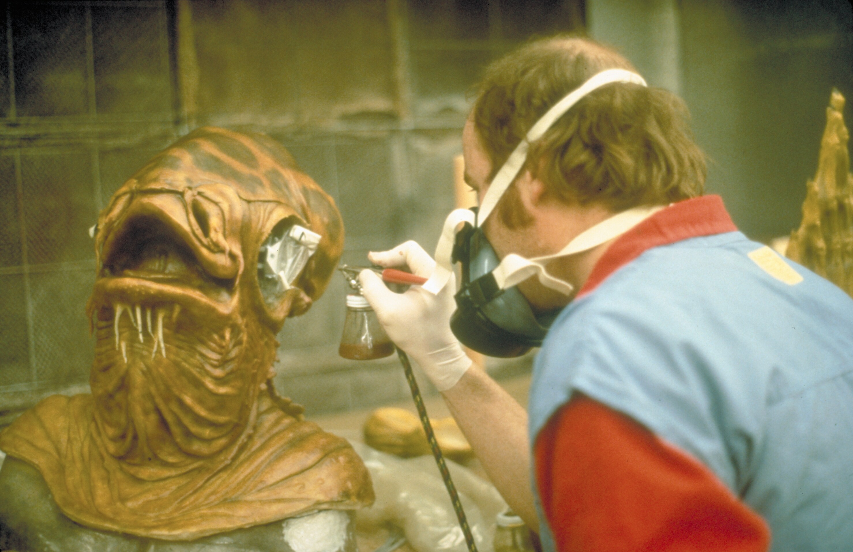 a man airbrushing a mask of an alien