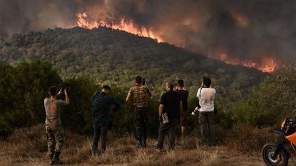 People standing in front of wildfires in Greece, taking photos