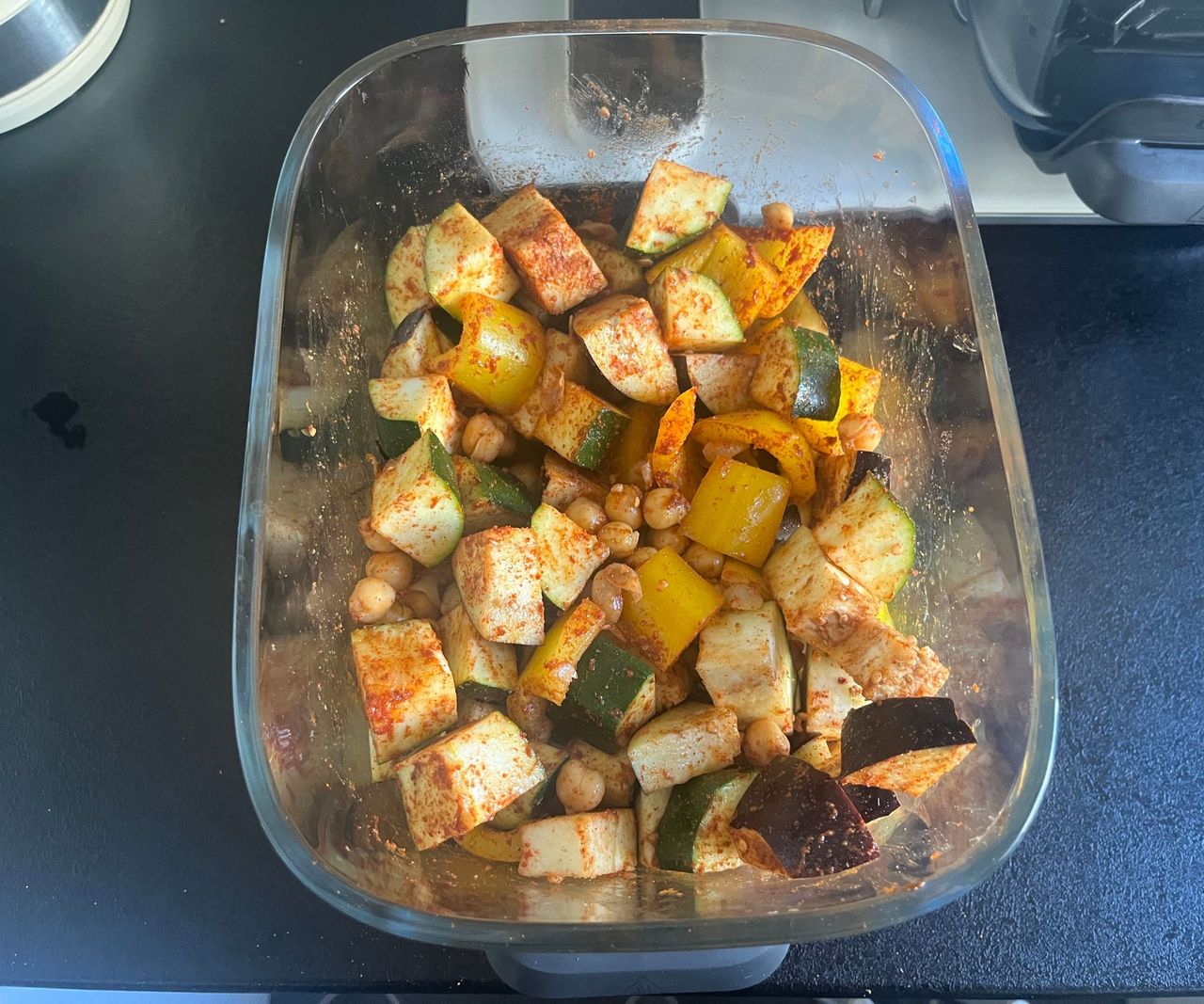 A glass air fryer basket filled with spiced vegetable chunks