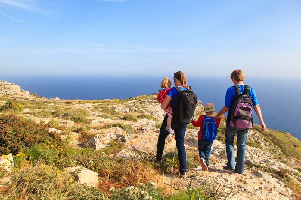 family with two kids hiking in summer mountains