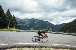 Image shows a rider cycling in the mountains