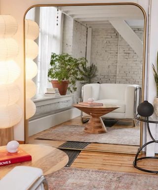 A gold mirror reflecting a gray seat and a coffee table