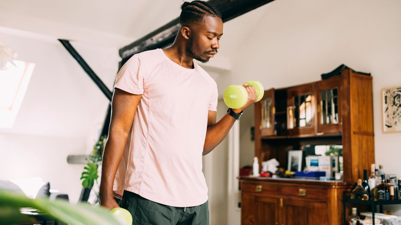 A man performing a biceps curl as part of a dumbbell workout at home 