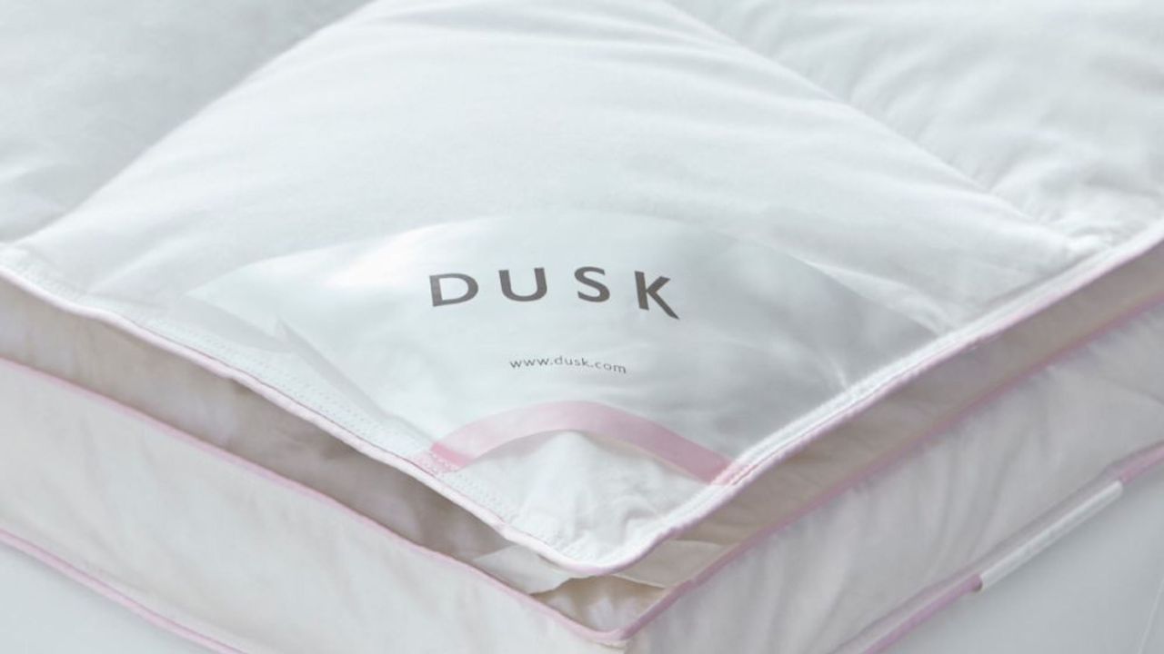 Dusk&#039;s Supreme Goose down mattress topper corner with pink piping and the dusk logo 