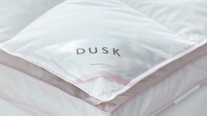 Dusk's Supreme Goose down mattress topper corner with pink piping and the dusk logo 