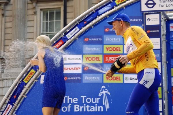 Tour of Britain winner Lars Boom sprays champagne on a podium girl.