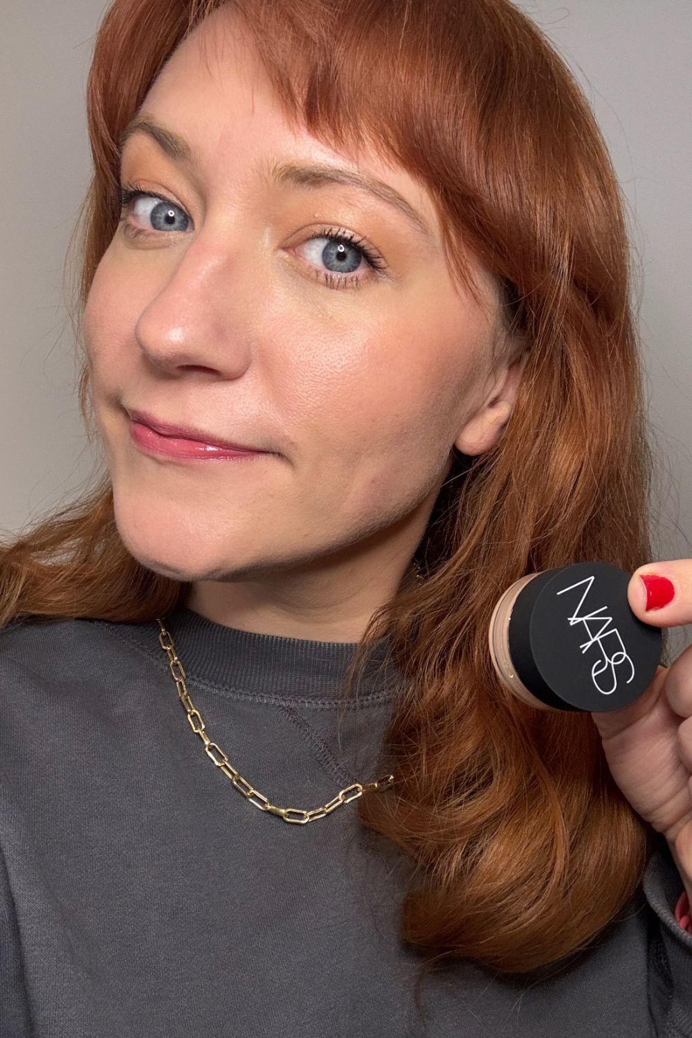 a headshot of matilda holding a pot of nars complete concealer